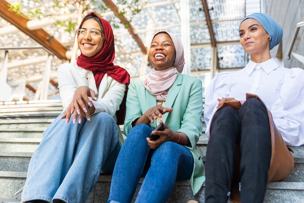 Multi-etnische groep moslimmeisjes die vrijetijdskleding en traditionele hijab-binding dragen en buiten plezier hebben - 3 arabische jonge meisjes