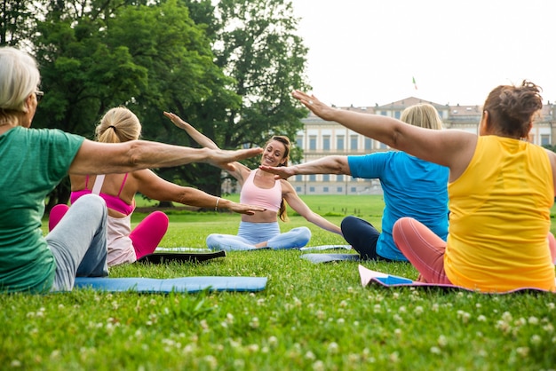 Multi-etnische groep oudere vrouwen die in het park trainen met fitnessinstructeur - Actieve ouderen die sporten in de natuur