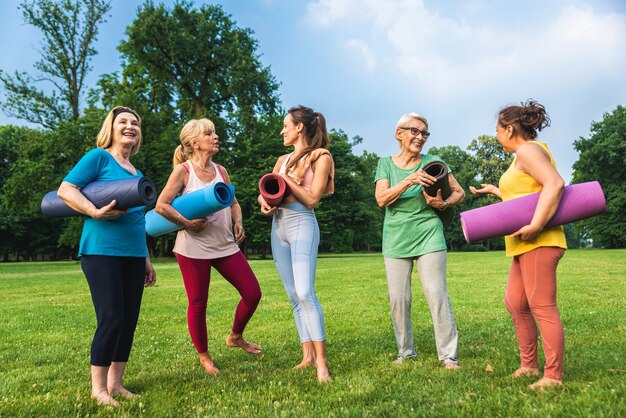 Multi-etnische groep oudere vrouwen die in het park trainen met fitnessinstructeur - Actieve ouderen die sporten in de natuur