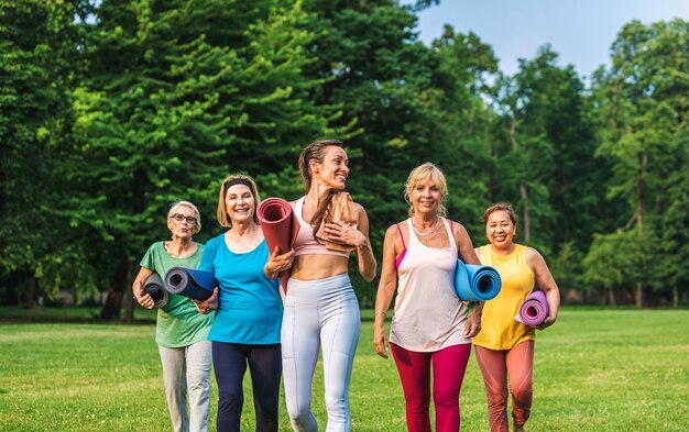 Multi-etnische groep oudere vrouwen die in het park trainen met fitnessinstructeur - Actieve ouderen die sporten in de natuur