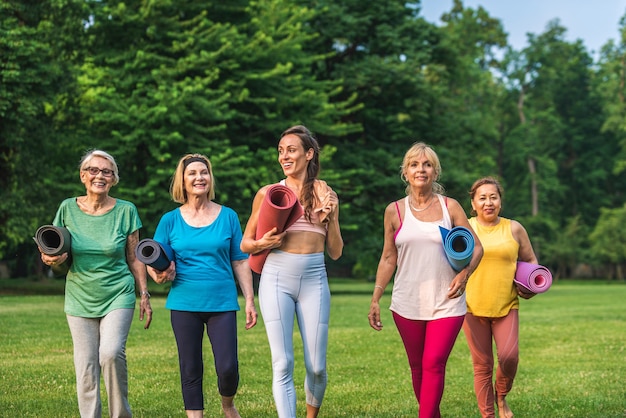 Foto multi-etnische groep oudere vrouwen die in het park trainen met fitnessinstructeur - actieve ouderen die sporten in de natuur