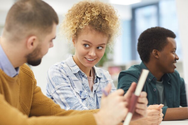 Multi-etnische groep studenten die aan bureau in de klas zitten