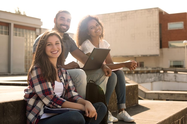 Multi-etnische groep studenten met laptop op campus - Soft sunset Light