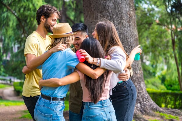 Multi-etnische groep verjaardagsfeest in het stadspark omarmd in een symbool van vriendschap voor altijd