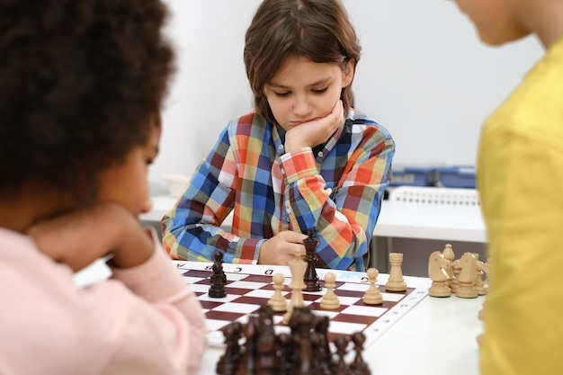 Multi-etnische kinderen die schaakbordspel spelen op school