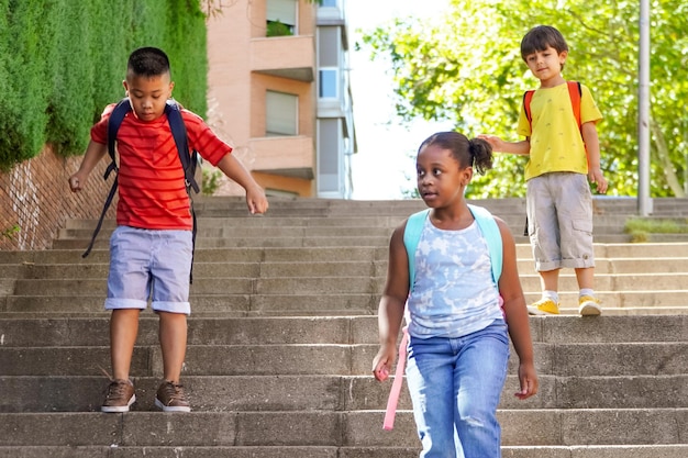 Multi-etnische kinderen met rugzakken op weg naar school