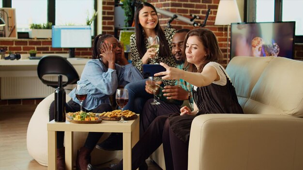 Multi-etnische vrienden die groepsfoto's maken met hun mobiele telefoon bij een appartementenbijeenkomst