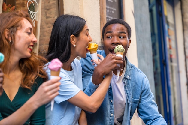 Multi-etnische vrienden in een ijssalon eten een ijs zomer leuk meisjespaar en multi-etnisch stel