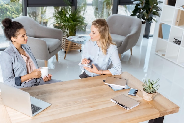 Multi-etnische zakenvrouwen bespreken nieuw zakelijk project terwijl ze op de werkplek op kantoor zitten