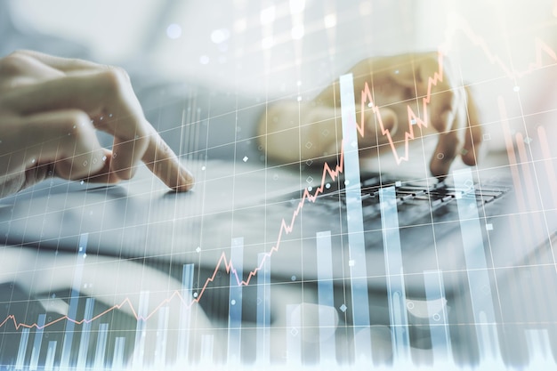 Multi exposure of abstract creative financial chart with hand typing on computer keyboard on background research and analytics concept