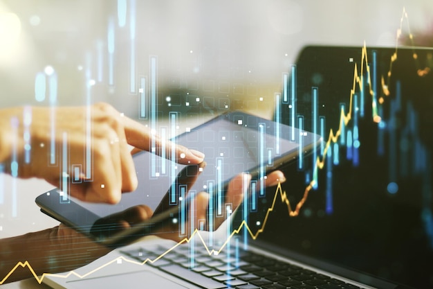 Multi exposure of abstract financial diagram and hand working with a digital tablet on background banking and accounting concept