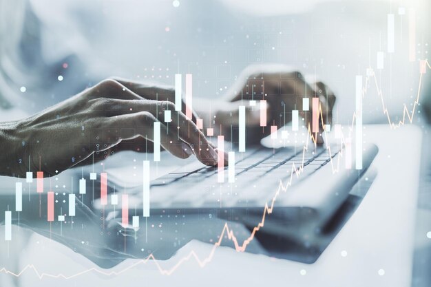 Multi exposure of abstract financial graph with hand typing on laptop on background financial and trading concept