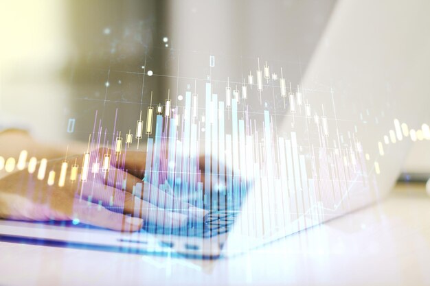 Multi exposure of abstract financial graph with hand typing on laptop on background financial and trading concept