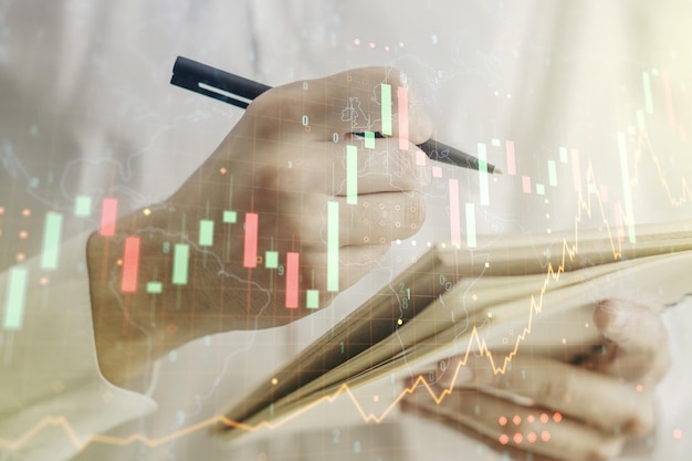 Multi exposure of abstract financial graph with world map and with man hand writing in diary on background financial and trading concept