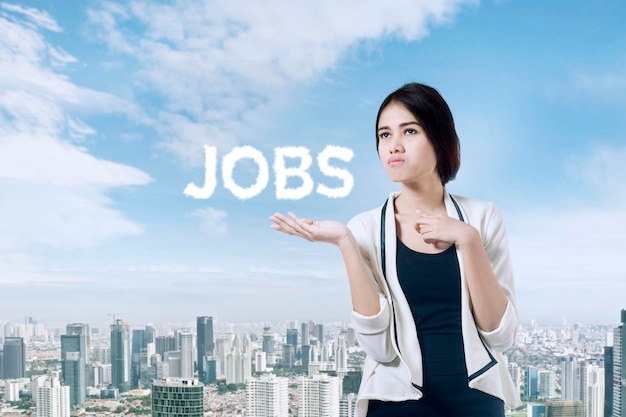 Multi exposure beeld van zelfverzekerde zakenvrouw met het woord JOBS over stadsachtergrond