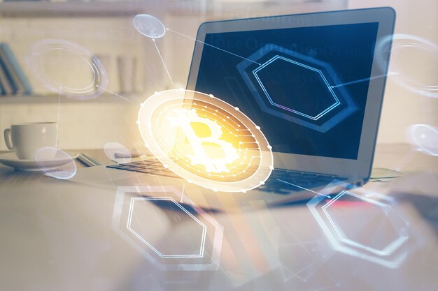 ブロックチェーンテーマのホログラムとコンピュータの背景のテーブルのマルチエクスポージャー ビットコインの暗号通貨の概念