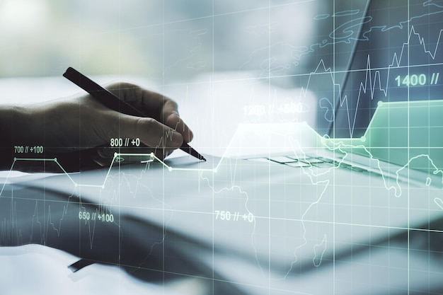 Multi exposure of creative statistics data hologram with hand writing in notebook on background with laptop stats and analytics concept