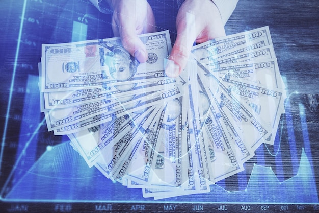 Multi exposure of financial graph drawing hologram and USA dollars bills and man hands Analysis concept