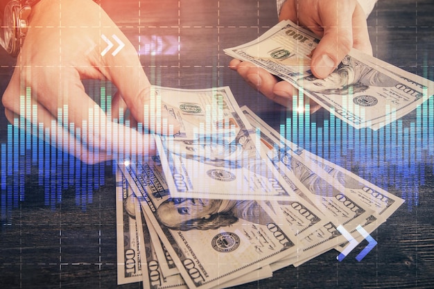 Multi exposure of financial graph drawing hologram and USA dollars bills and man hands Analysis concept