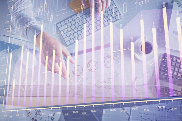 Multi exposure of mans hands typing over computer keyboard and forex graph hologram drawing Top view Financial markets concept