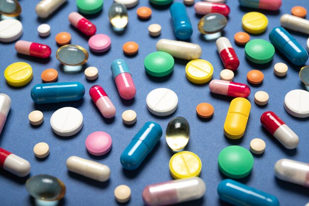 Multi-gekleurde pillen op een blauwe ondergrond. Geneeskunde en gezondheid.