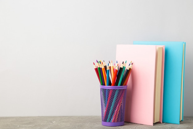 Multi gekleurde schoolboeken en potloden op grijs