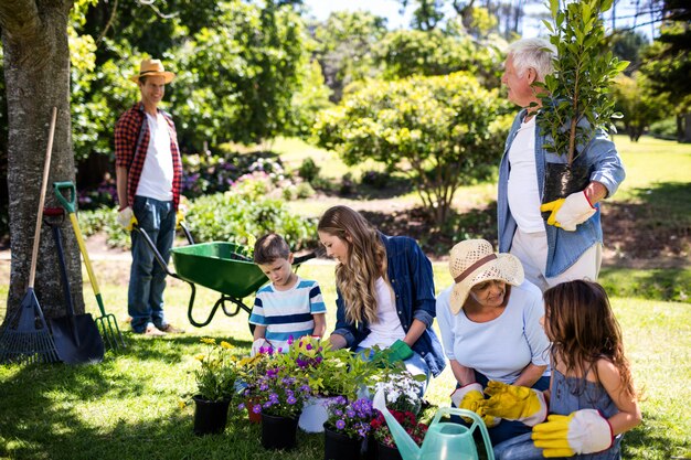 Foto famiglia di diverse generazioni che fa il giardinaggio nel parco