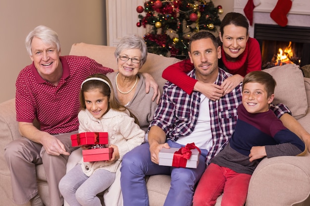 Multi generation family holding gifts on sofa