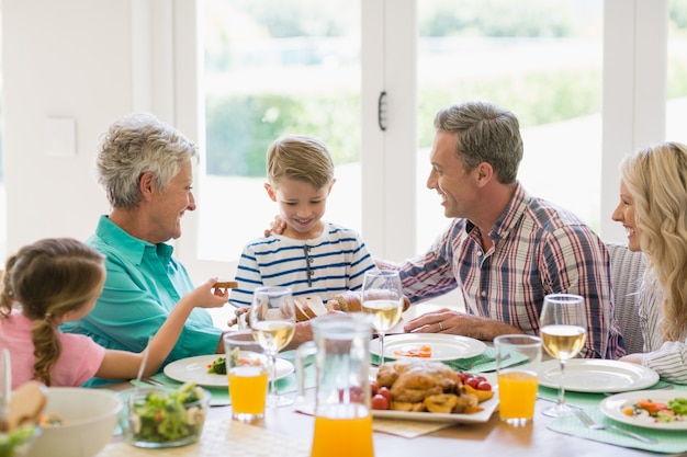 Multi- generation family interacting while having meal on dinning table