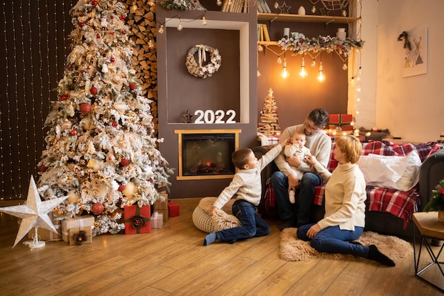 현대적으로 장식된 집에서 크리스마스 트리 근처의 다세대 가족 새해 복 많이 받으세요