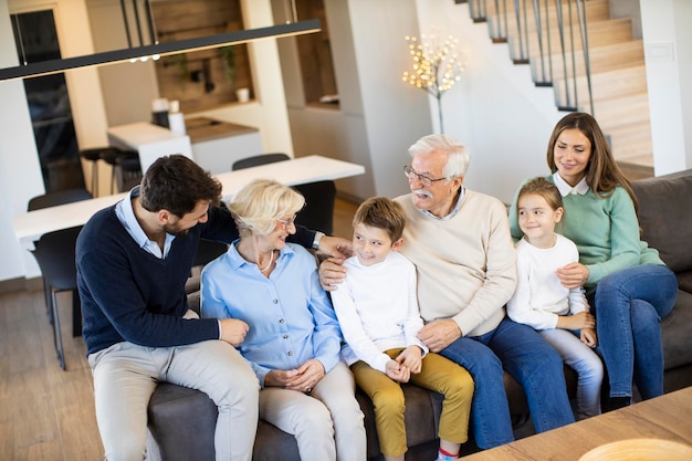 Multi generation family sitting together on the sofa at modern home and watching TV