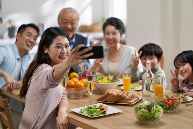 Photo multi generational asian family taking a selfie at dining table