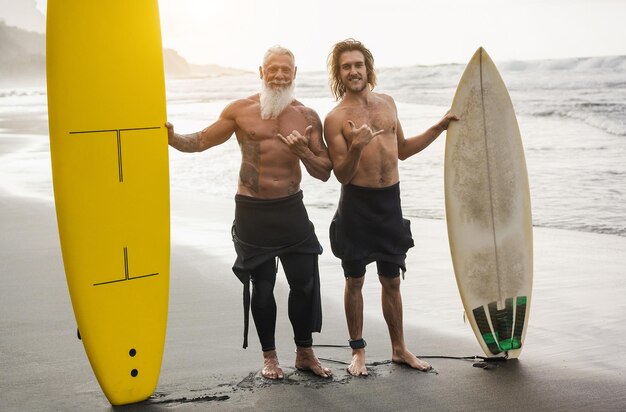 Multi generational family having fun while surfing on beach focus on guy face