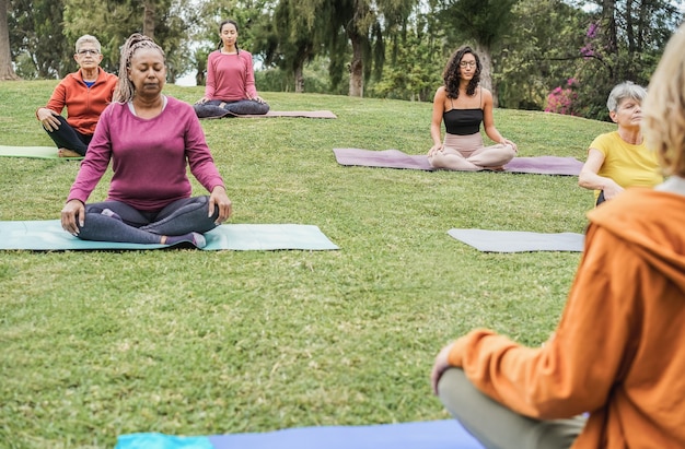 Multi generational people doing yoga class at city park - Focus on left senior woman face