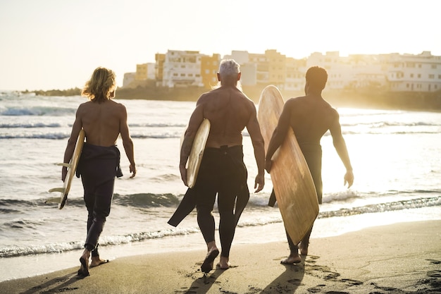 해변에서 서핑을 하며 즐거운 시간을 보내는 여러 세대의 서퍼 친구들 - 노인에 대한 주요 초점