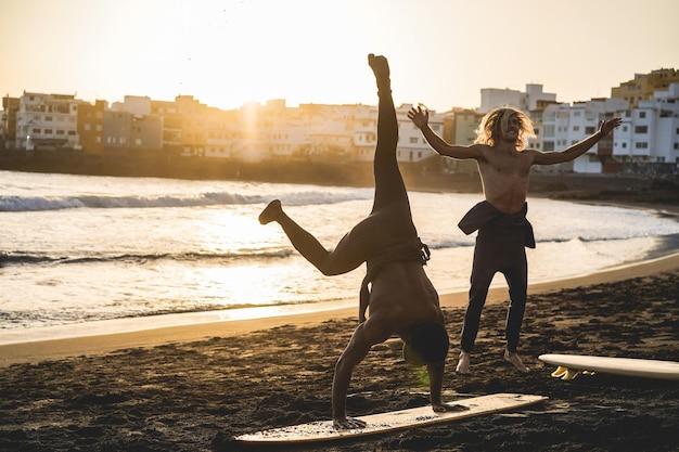 Multi generational surfer men doing warm up on the beach before surf session  Soft focus on african man