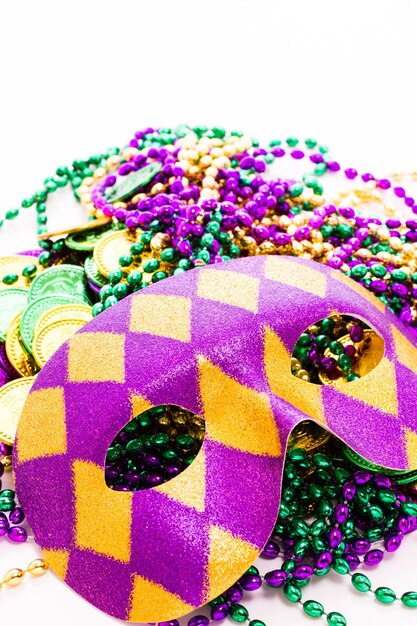 Foto multi kleur mardi gras kralen, tokens en masker op witte achtergrond.