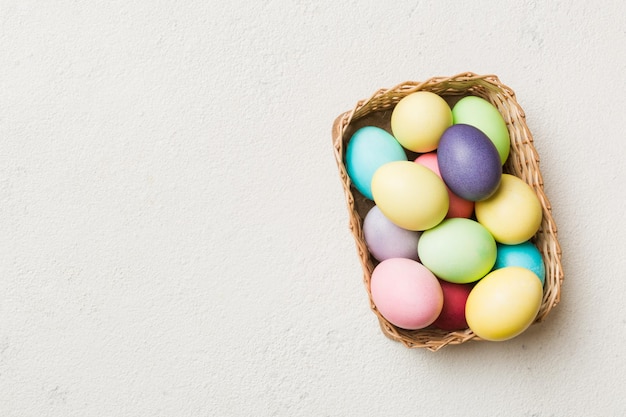 Multi kleuren paaseieren in de geweven mand op gekleurde achtergrond pastelkleur paaseieren vakantieconcept met kopieerruimte