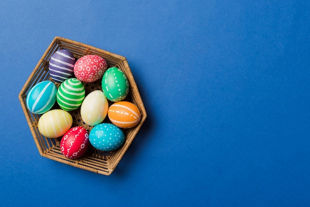 Multi kleuren paaseieren in de geweven mand op gekleurde achtergrond Pastelkleur paaseieren vakantieconcept met kopieerruimte