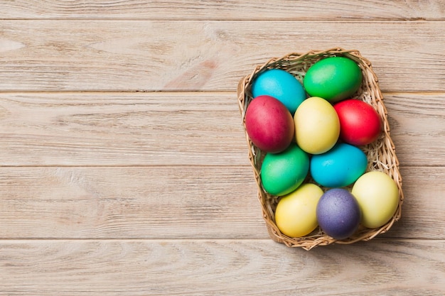 Multi kleuren paaseieren in de geweven mand op gekleurde achtergrond Pastelkleur paaseieren vakantieconcept met kopieerruimte