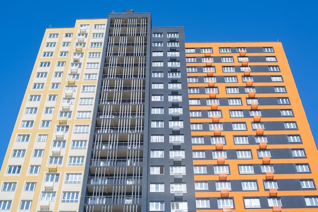 外の高層住宅。長屋、ボトムアップビュー。日中の青い空を背景にした色とりどりのモダンな建物。