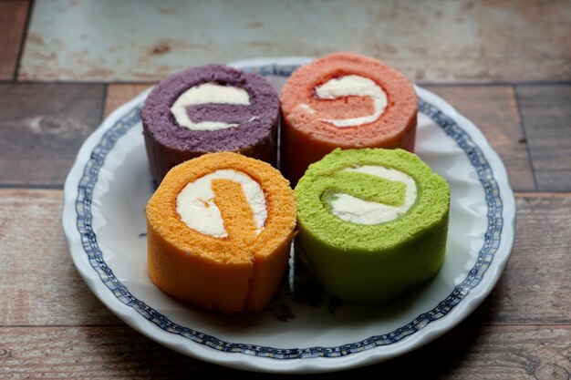 Torta di rotolo di marmellata multicolore sul piatto su un tavolo di legno