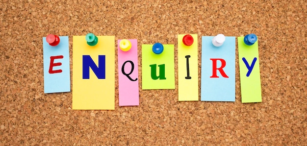Multicolor notes with letters pinned on a cork board Word ENQUIRY