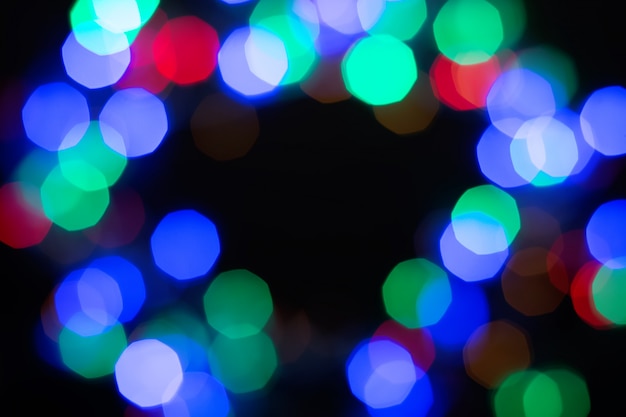 Multicolor shiny bokeh frame on black background. Abstract black, green, purple, red and blue glitter