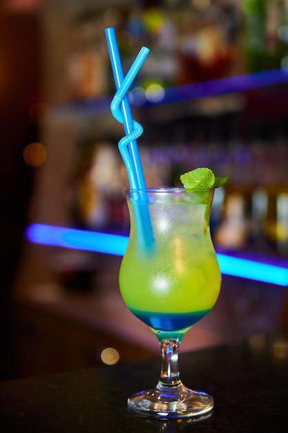 Multicolored alcoholic cocktail with mint leaves on the bar counter