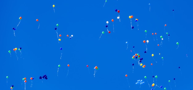 Photo multicolored balls filled with helium fly in the blue sky