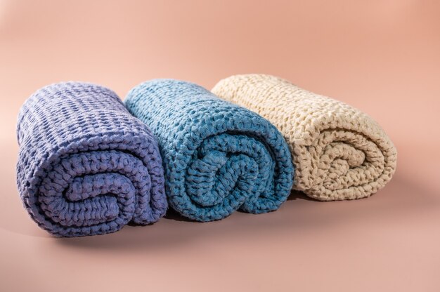 Multicolored bath and spa towels twisted into a roll on pink