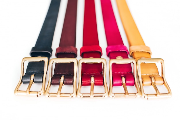 Multicolored belts. a lot of leather belts on a white background. red, yellow, blue, brown, green belts are carved on a white