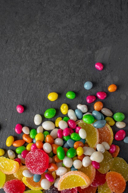 Multicolored bright candies and marmalade photo from above on a dark background