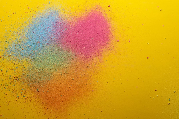 Multicolored bright powder scattered on a yellow background